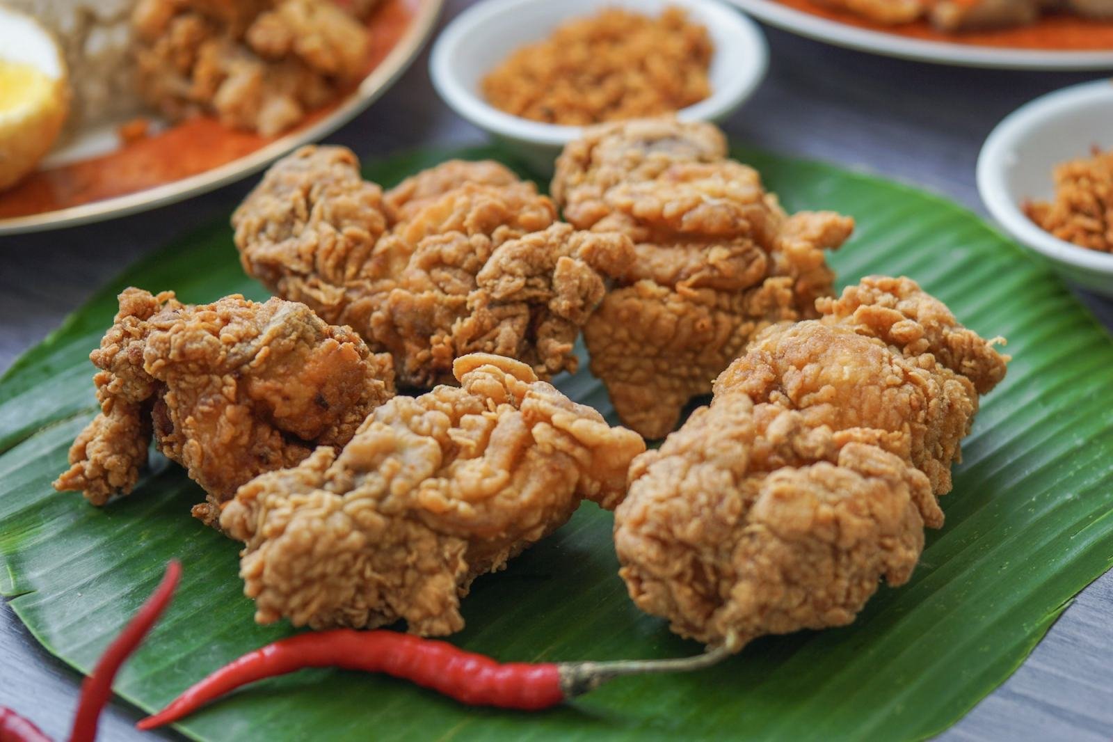 Ayam goreng crispy di atas daun pisang, dengan cabai dan sambal